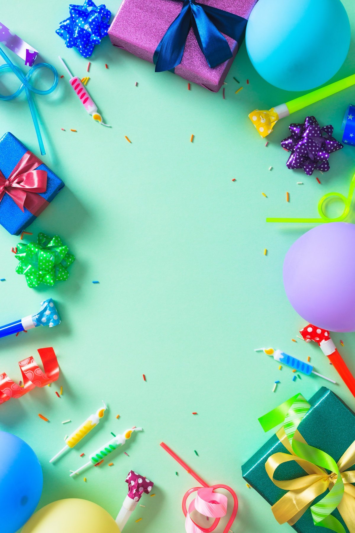 A festive border of colorful gifts, balloons, and party favors on a mint green background