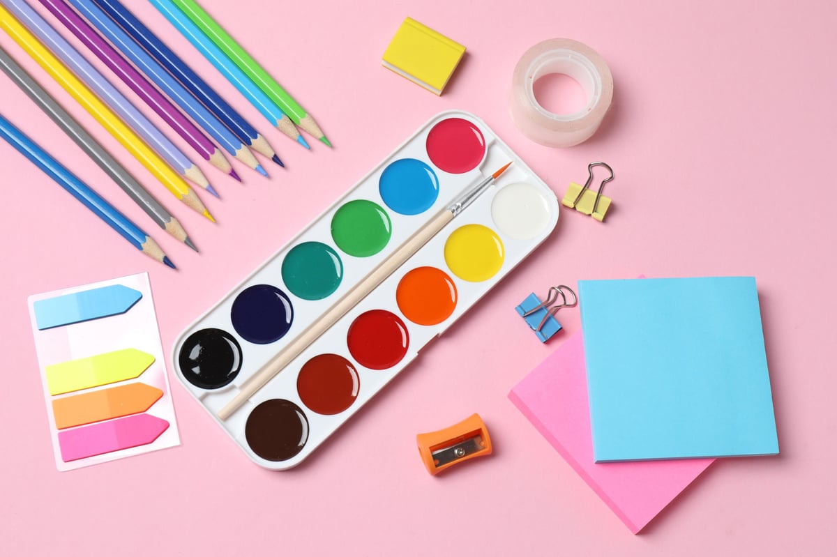 School supplies and art materials on pink background